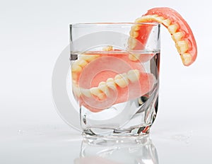 A set of dentures in a glass of water