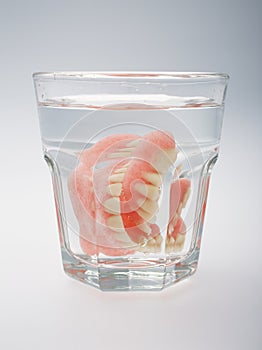 A set of dentures in a glass of water