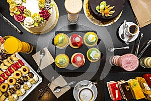 Set of desserts and cake on a black table, cream chocolate, icing