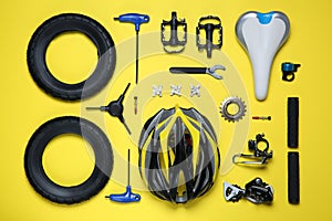 Set of different bicycle tools and parts on yellow background, flat lay