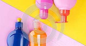 Set of different bottles for cleaning, on a yellow-pink background