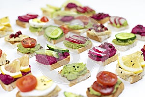 Set of different bruschetta sandwiches with beet hummus, guacamole, different vegetables. vegetarian helsifood concept. summer