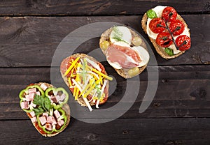 Set of different bruschettas on dark wooden table. Top view and copy space.