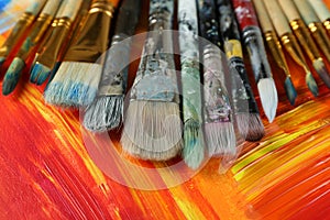 Set of different brushes on abstract colorful paint, closeup