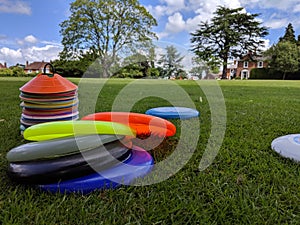 A set of different coloured ultimate frisbees piled up on the grass