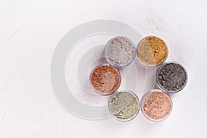 Set of different cosmetic clay mud powders on white