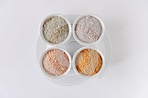 Set of different cosmetic clay mud powders on white background