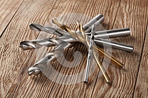 Set of different drill bits on wooden background