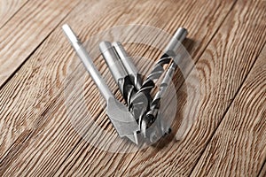Set of different drill bits on wooden background