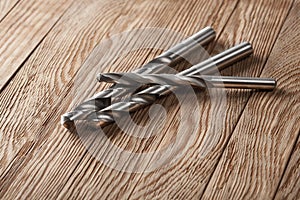 Set of different drill bits on wooden background