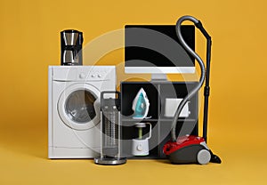 Set of different home appliances with vacuum cleaner on background