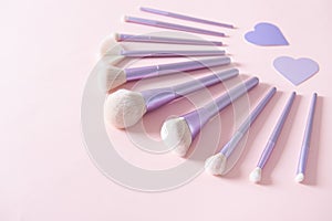 Set of different make up brushes, favourite make up tools on pink background with hearts. Professional make up brushes for