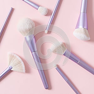 Set of different make up brushes, violet make up tools on pink background. Professional make up brushes for visagist. Cosmetic