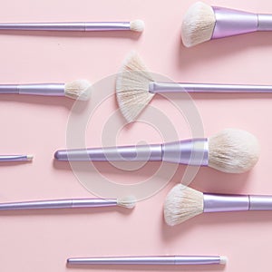 Set of different make up brushes, violet make up tools on pink background. Professional make up brushes for visagist. Cosmetic
