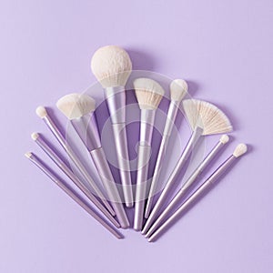 Set of different make up brushes, violet make up tools on violet background. Professional make up brushes for visagist. Cosmetic