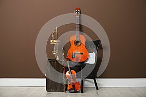 Set of different musical instruments near brown wall indoors