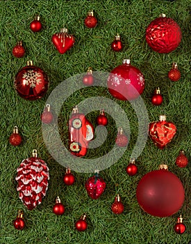 A set of different red Christmas toys on a green background of Christmas tree needles. Red ball. Decor and decorations