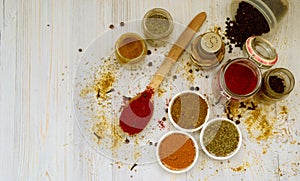 A set of different seasonings is on the table in different containers. pepper, paprika, cloves, herbs