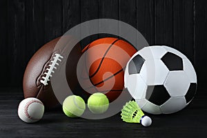 Set of different sport balls and shuttlecock on black wooden table