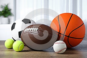 Set of different sport balls on wooden table indoors