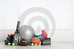 Set of different sports equipment on white floor indoors, space for text