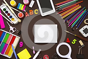Set of different stationery, school notebook alarm clock and supplies on brown background. Back to school concept. Banner format.