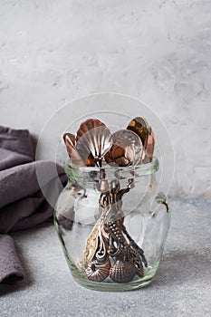 A set of different teaspoons in a glass jar. Gray background with copy space