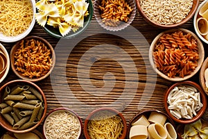 Set of different types of pasta in a bowls on a wooden background