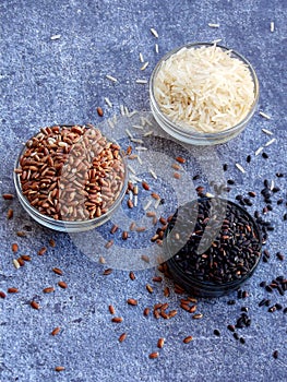 Set of different types rice on grey background: white glutinous, black, basmati, brown and mixed rice. Healthy concept. Top view.