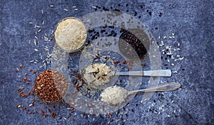 Set of different types rice on grey background: white glutinous, black, basmati, brown and mixed rice. Healthy concept. Top view.