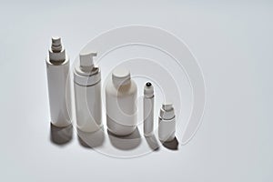 Set of different white bottles for beauty products arranged in the descending order of height isolated over white