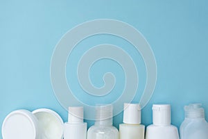 Set of different white plastic cosmetic bottles on blue background, abstract skin and body care copy space