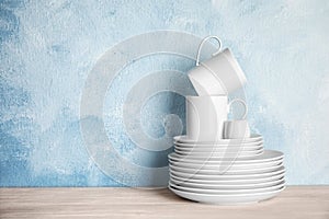 Set of dinnerware on table against color background with space for text.