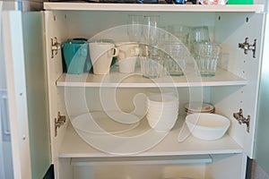 Set of dishes and glass in cabinet at apartment or Home. Kitchenware, dinnerware, lifestyle domestic concept