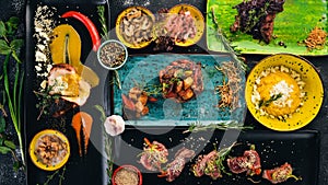 A set of dishes of meat and fresh vegetables and fish on a wooden table.