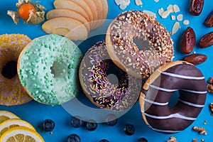 Set of donuts with different kinds of topping and fruits on blue paper background.