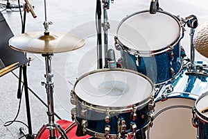 Set of drums, cymbals and microphones on pavement background