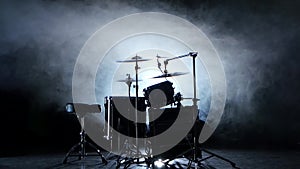 Set of drums, cymbals and other percussion instruments. Black smoky background. Back light.