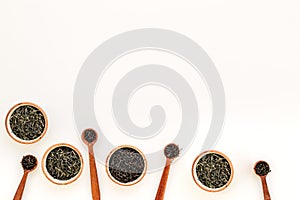 Set of dry tea leaves in bowls and spoons for tea ceremony on white background top view copy space