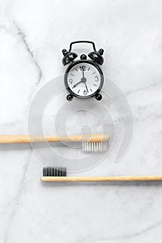 Set of eco-friendly toothbrushes, toothpaste, clock on marble background. Dental and healthcare concept.