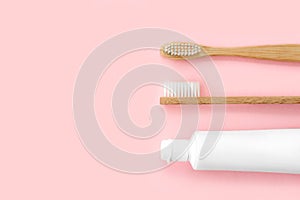 Set of eco-friendly toothbrushes and toothpaste on pink background.