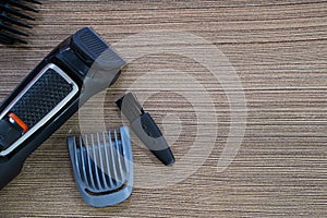 Set of electric hair clippers and attachments on wooden table. Closeup