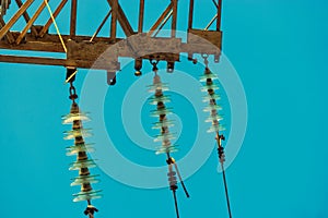 Set of electrical insulator with wires mounted on rusty power tower in front of the the blue sky