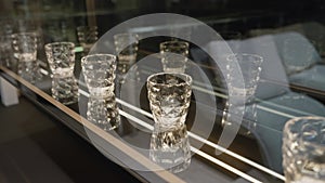 A set of empty empty glasses displayed in rows. There are beautiful crystal glasses for vodka on display. Lots of