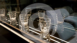 A set of empty empty glasses displayed in rows. There are beautiful crystal glasses for vodka on display. Lots of