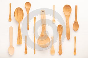 set of empty wooden spoons of different sizes with over white background, trendy flat lay