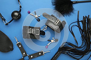 Set of erotic toys for BDSM on blue background. The game of sexual slavery with a whip, gag and leather blindfold. Intimate sex