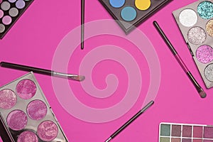 Set of eye shadow . Make up products on pink background with empty space at center. Makeup brushes and colorful