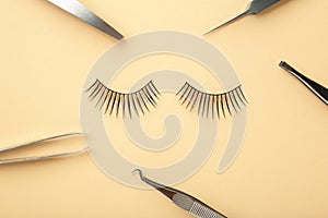 Set of false eyelashes extencions on beige background with tweezers. Minimalism