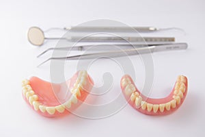 Set of false teeth and dental tools on white background
